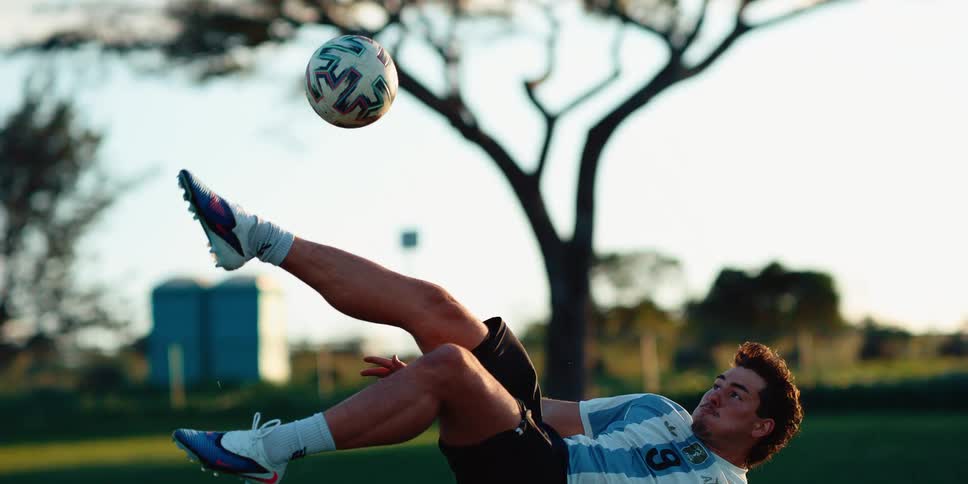 Player performing a bicycle kick to strike a soccer ball suspended in the air