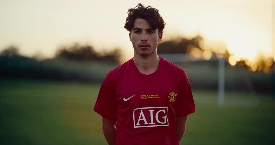 Young man stands on a soccer field near sunset in the summer