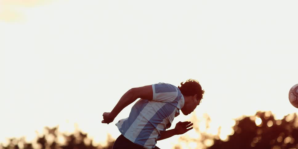 Player leaps into the air and hits the soccer ball with his forehead