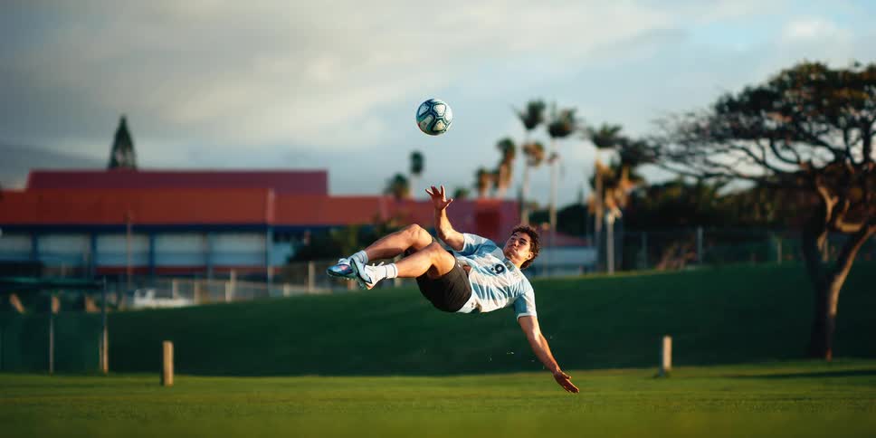 Soccer player falls backwards and kicks the ball while in mid air