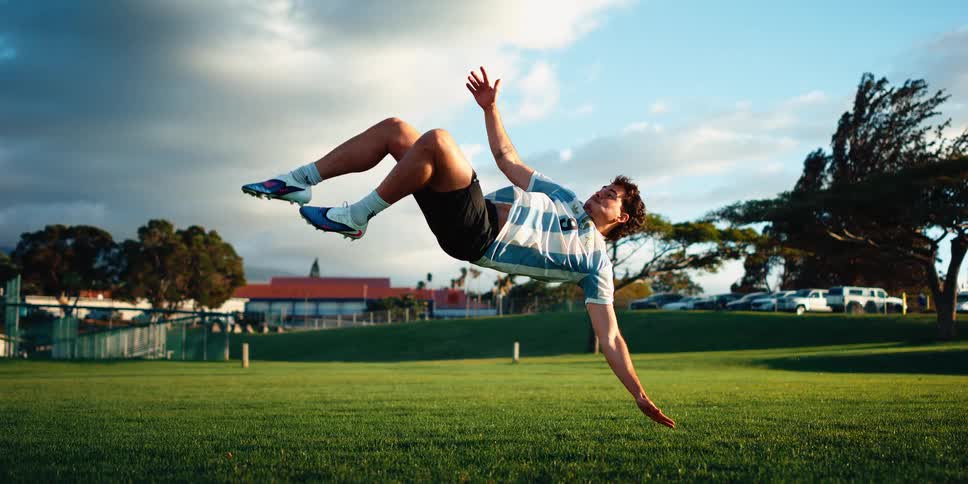 Soccer player falls backwards and kicks the ball while in mid air