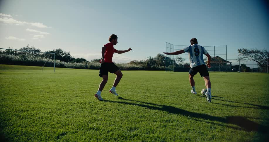 Two players contesting the ball on a grass soccer field during an outdoor match