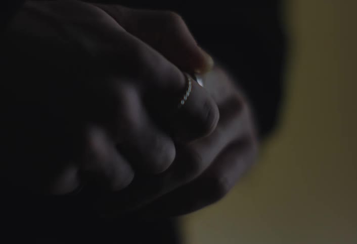 Person removes a ring from their finger with the other hand