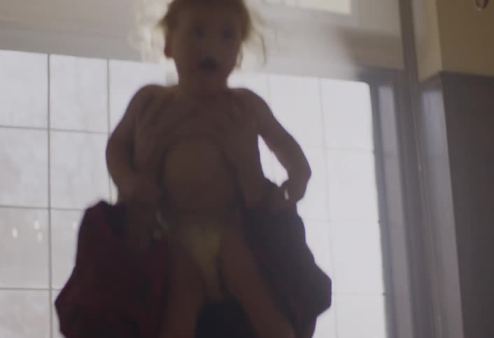 Mother playing with her young son on her lap in a room of the house