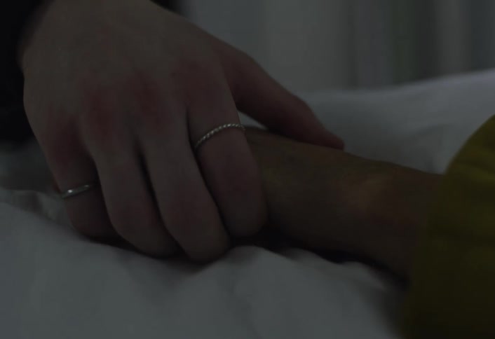 Hand holding the wrist of a person lying in a bed