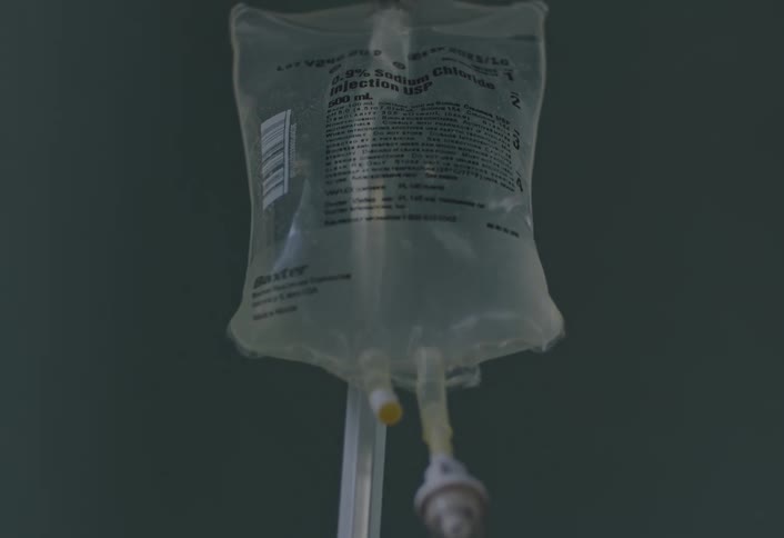 A hanging iv bag full of a clear liquid in a room