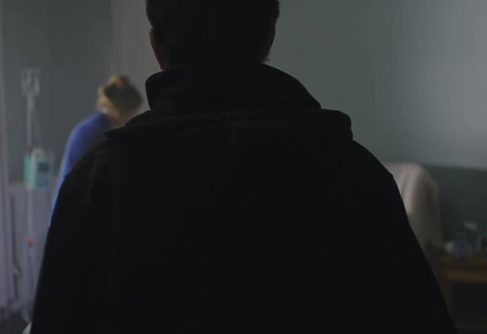Man entering a room with a woman beside a bed