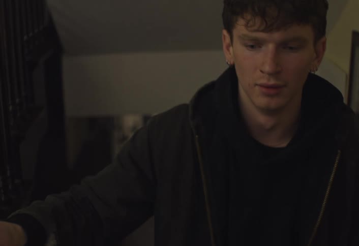 A man that looks sad walking up a staircase in a house