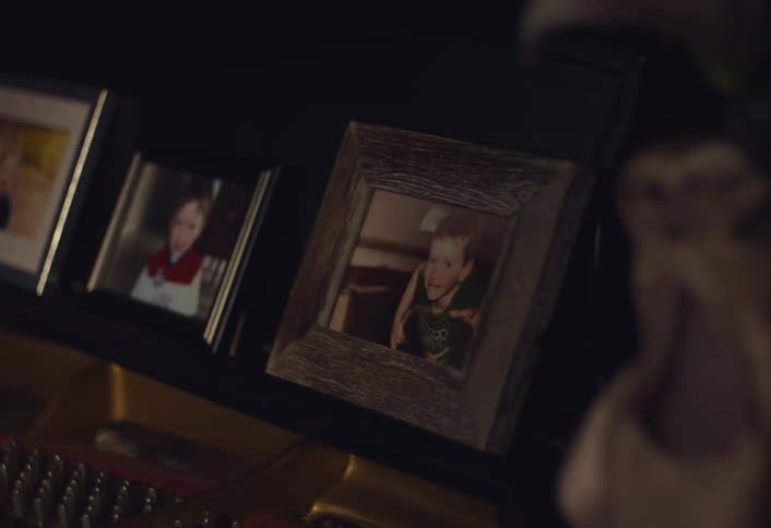 A close p of a dimly lit room with a shelf of a few pictures of happy children