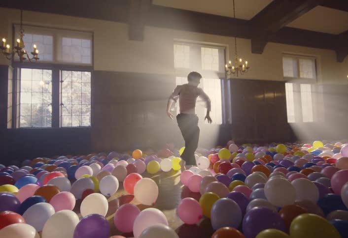 A man dancing in a room full of balloons