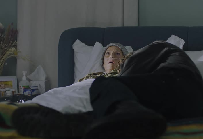 A man crying while laying in a hospital bed with an elderly woman