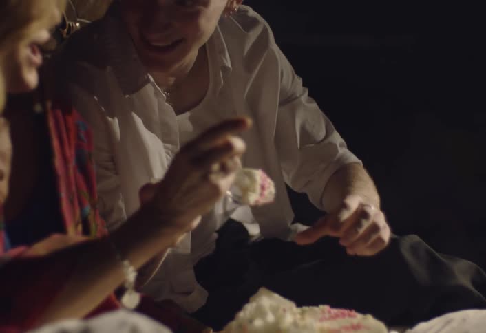 Man and woman eat cake while sitting side by side
