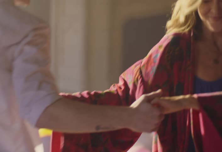 Woman and man dance facing each other in a lit hall