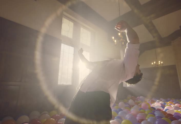 Young man dances in a sunny room with a floor covered in balloons