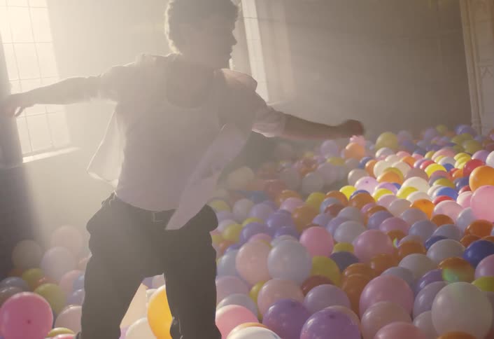 A man dancing in a room full of balloons