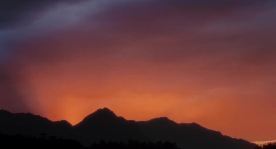 Mountain silhouettes against an orange sky at sunset
