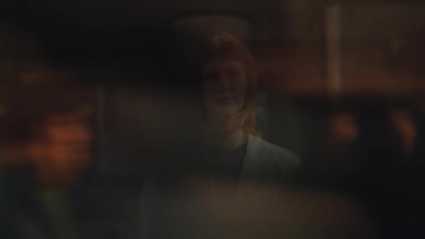 Woman stands still while people pass blurred in front of her