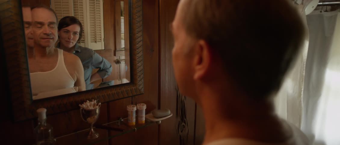 Man and woman smile while looking to mirror