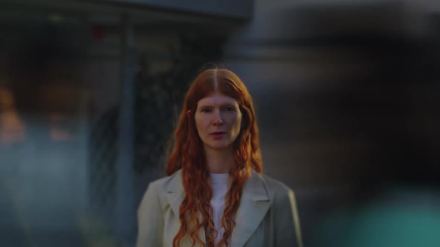 Woman stands still while people pass by blurred around her