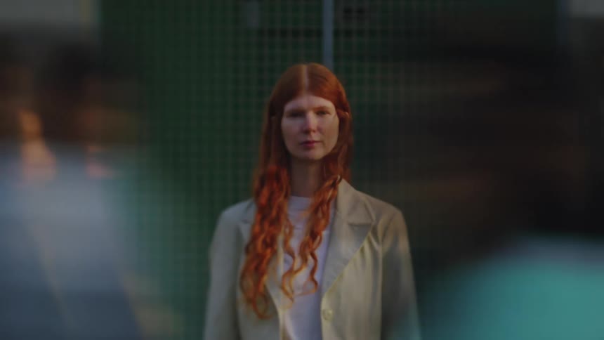 A woman in front of a building stands still as other people rush past her