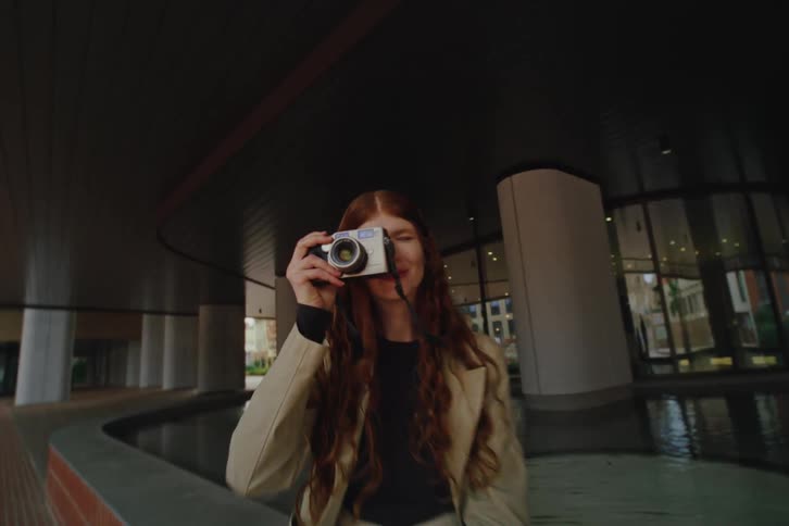 Woman sitting by a reflecting pool takes a photo with a camera