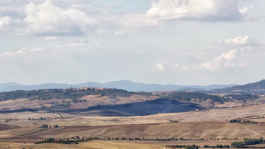 Rolling hills with agricultural fields under a partly cloudy sky