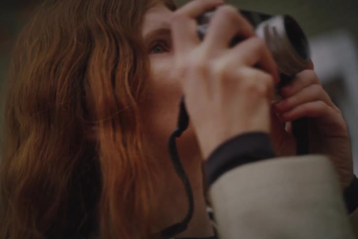 Woman raises a camera to her face to take a photo