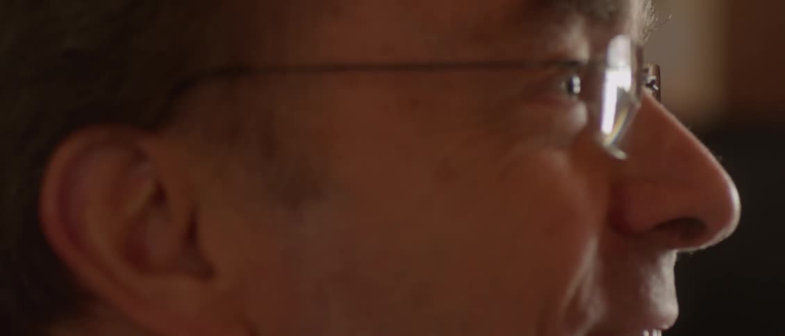 A man with glasses smiles