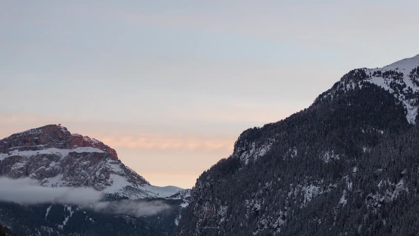 A time lapse of a sunset over a mountain covered in snow