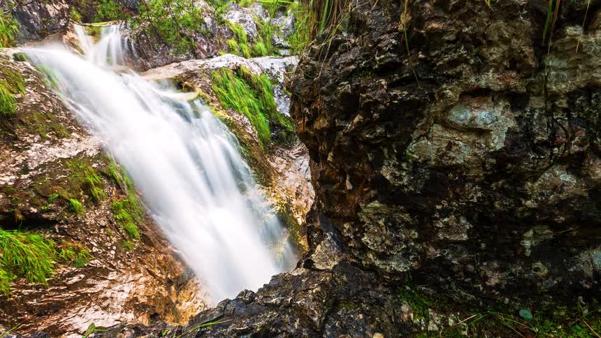 A waterfall flows into a small pool of water beneath it