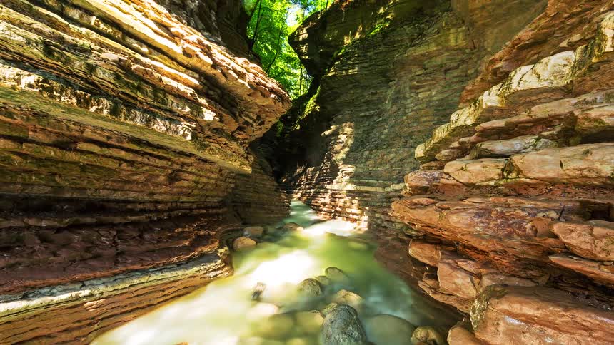 A river flows over rocks at the bottom of a canyon