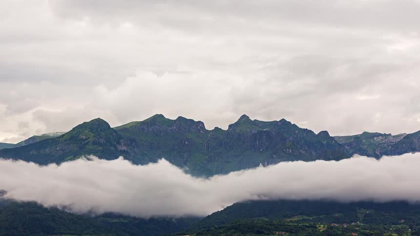 A time lapse of clouds in front of a mountain