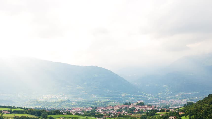 Clouds pass low over a city in the mountains