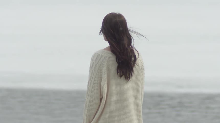 Long haired girl looks longingly out towards water