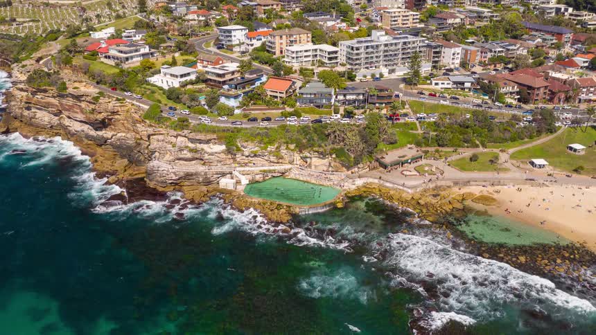 Ocean waves wash upon the cliffs where a coastal city is located