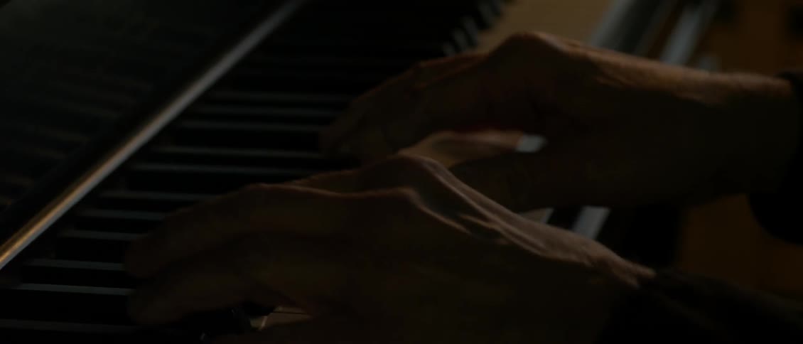 A person is playing the piano in a dark room