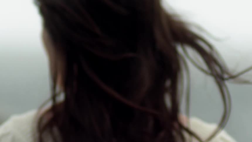 A woman is standing outside on a windy day