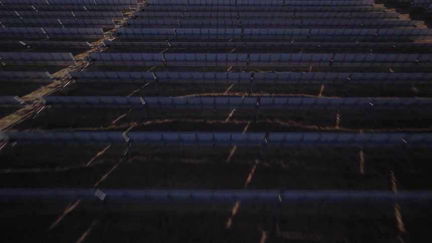 Aerial footage of a large solar panel farm with numerous rows