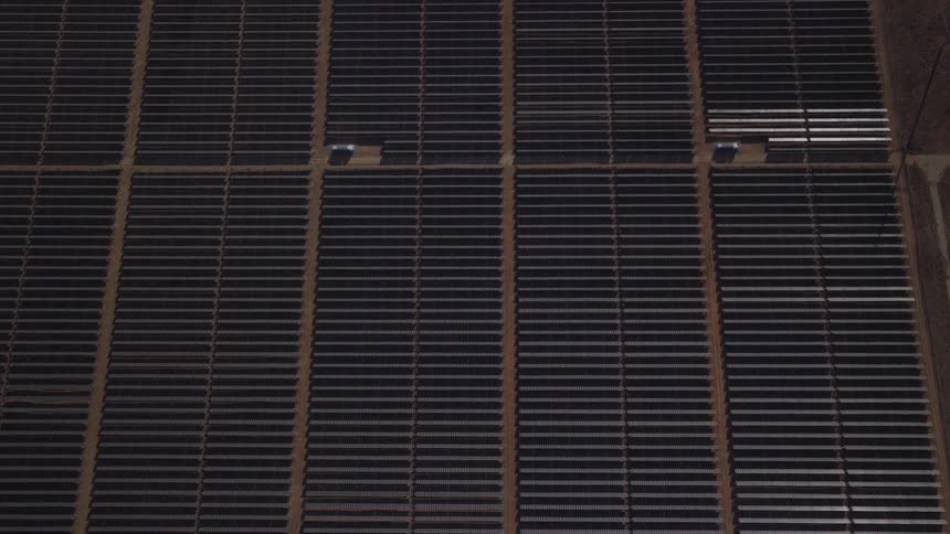 Overhead aerial footage of a large solar panel farm with numerous rows