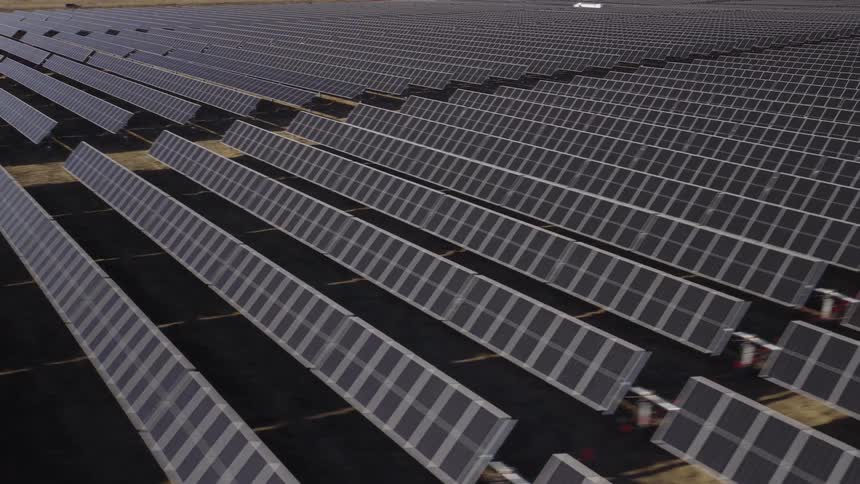 An aerial view of a lot of solar panels in a field