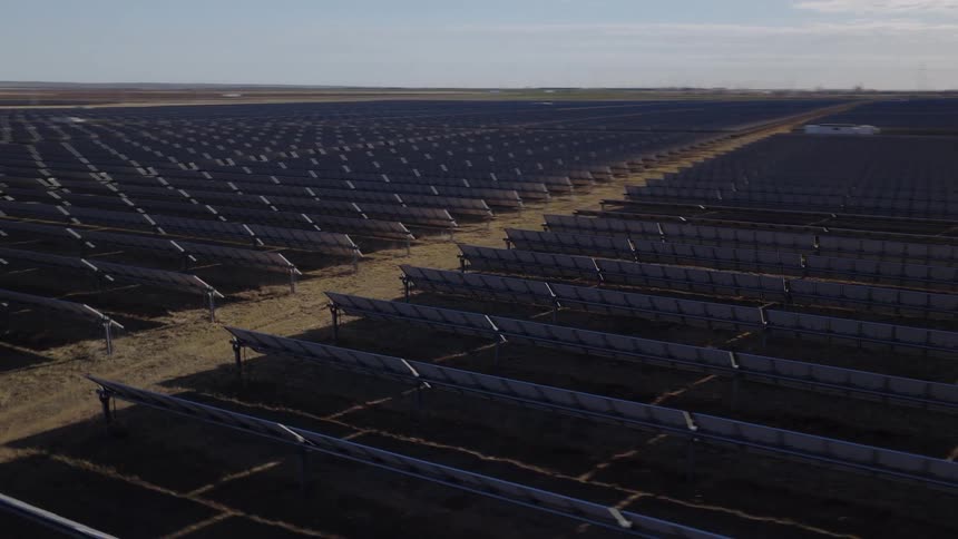 Aerial view of a massive solar panel farm stretching across a flat rural landscape generating renewable energy