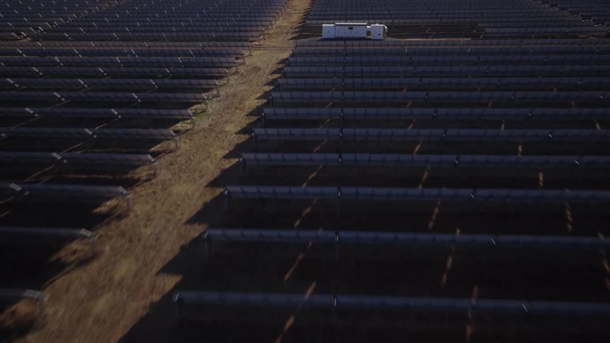Aerial view of a large solar panel farm with rows of photovoltaic panels in a desert landscape