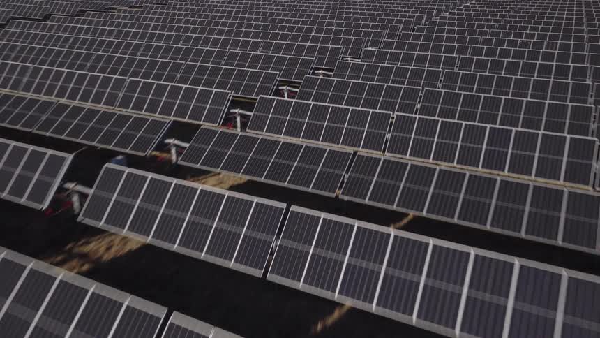 A vast array of solar panels is installed in rows across a dark outdoor landscape