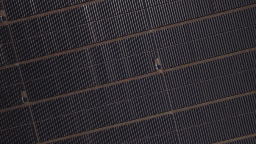 Aerial view of vast solar panel arrays forming precise diagonal rows across the landscape