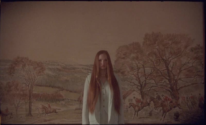 A woman wearing a nightgown is standing in front of a large painting