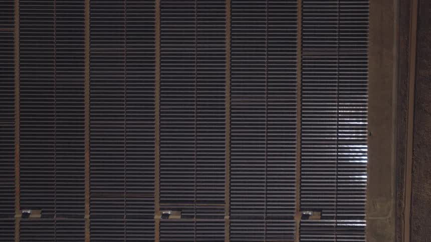 Aerial top down view of a grid of solar panels installed on a rooftop generating renewable energy