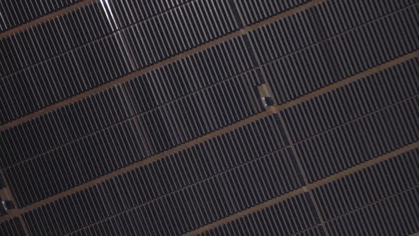 Aerial view of vast solar panel arrays forming precise diagonal rows across the landscape