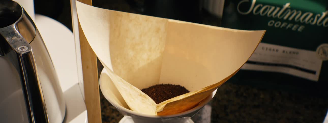 Person puts coffee grounds into a paper filter