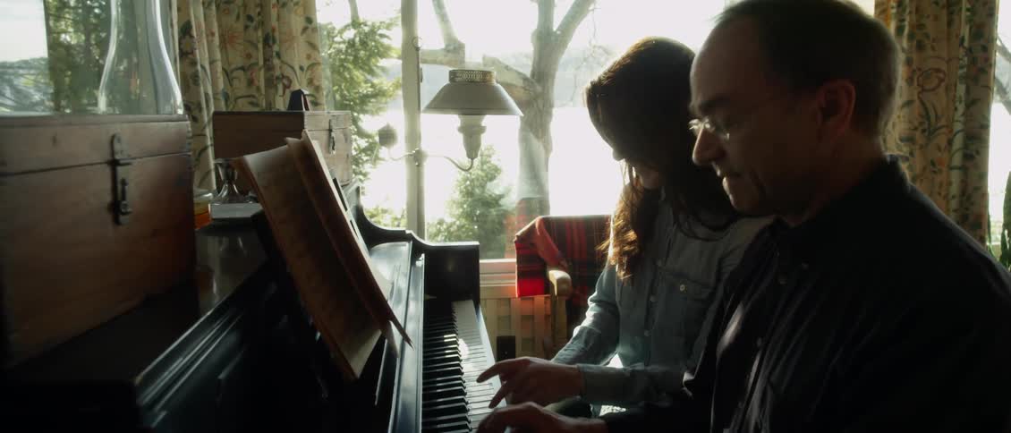 A man and woman play together on a piano