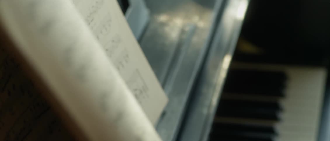 A man flips through a music book while sitting at a piano